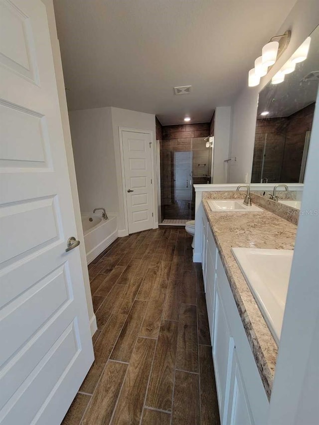 full bathroom with vanity, toilet, wood-type flooring, and independent shower and bath