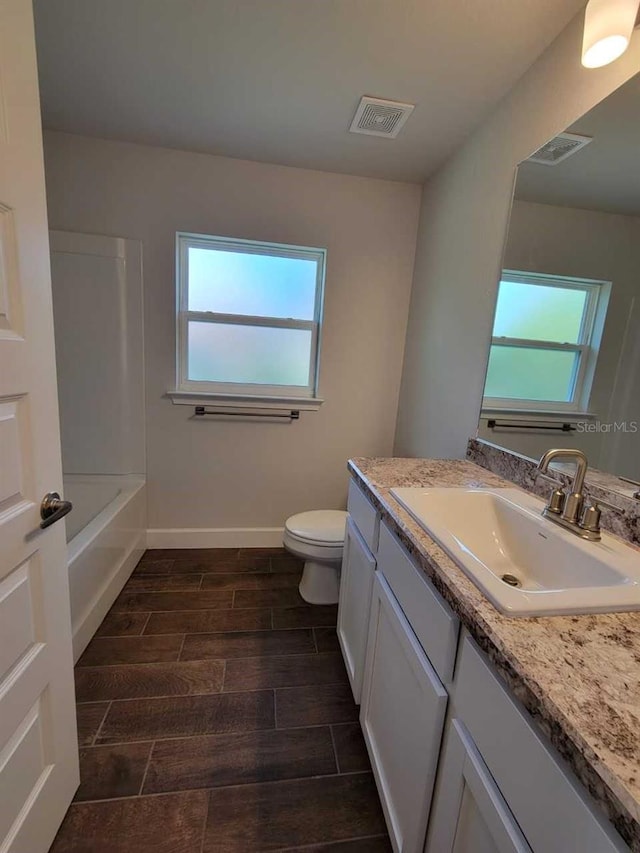 bathroom featuring a wealth of natural light, vanity, wood-type flooring, and toilet