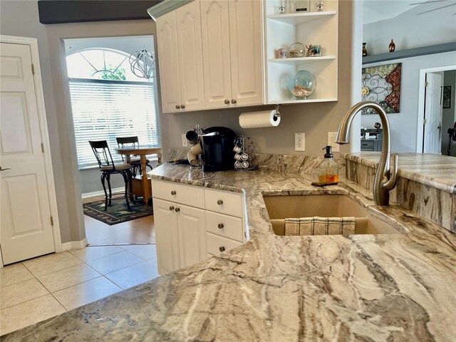 kitchen featuring light stone counters, sink, white cabinets, and light tile patterned floors