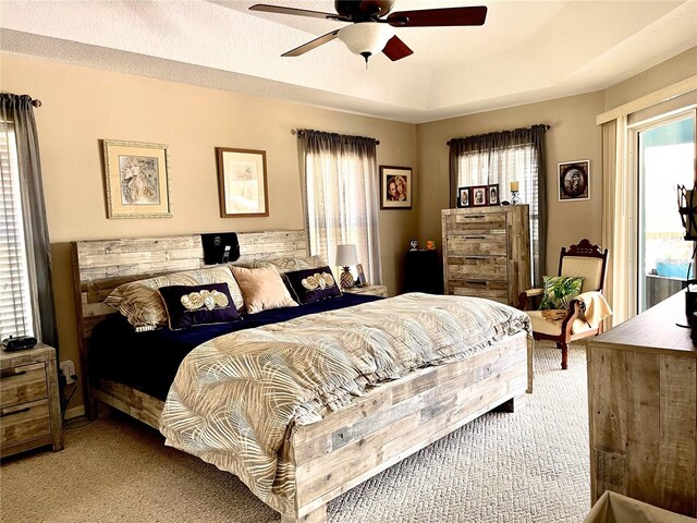 carpeted bedroom with a tray ceiling, ceiling fan, and a textured ceiling