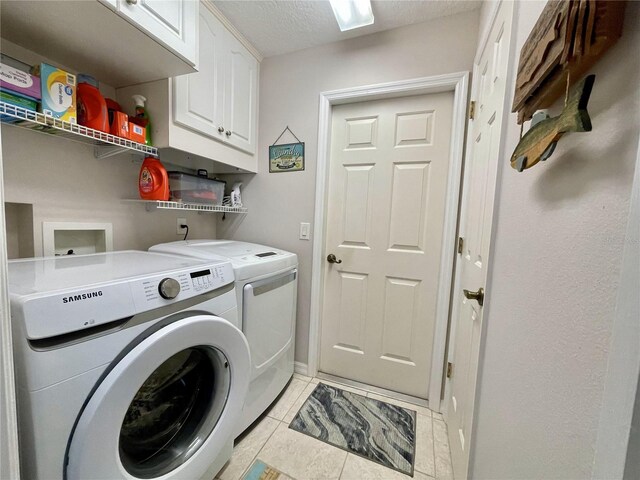 laundry room with washer and clothes dryer, light tile patterned floors, cabinets, and a textured ceiling