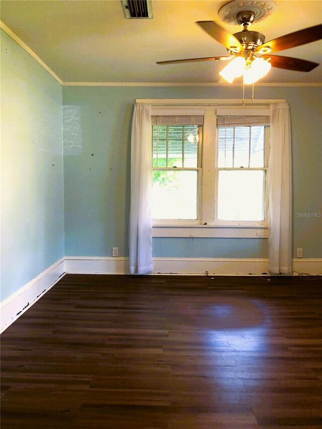 empty room with ceiling fan, crown molding, and dark wood-type flooring