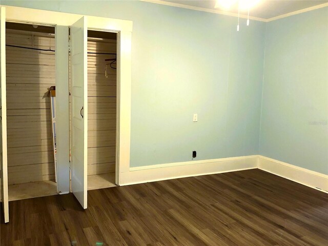 unfurnished bedroom with dark hardwood / wood-style flooring, a closet, and crown molding