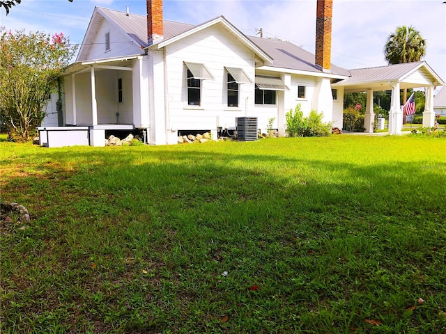 rear view of property featuring central air condition unit and a lawn