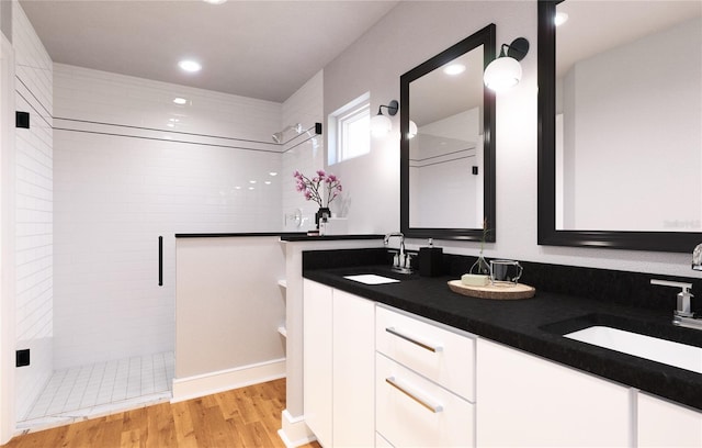 bathroom featuring dual vanity, a tile shower, and hardwood / wood-style floors