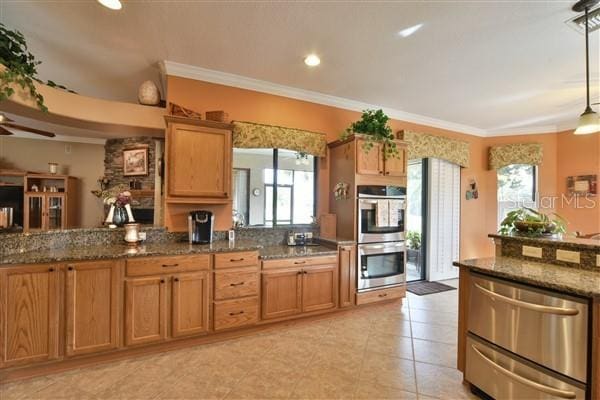 kitchen featuring pendant lighting, stainless steel appliances, crown molding, and dark stone countertops