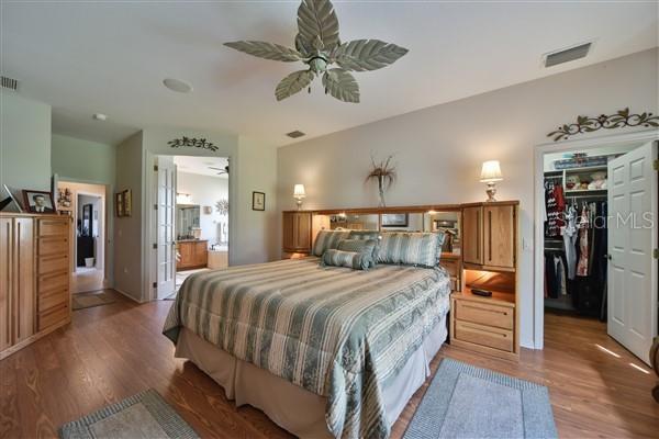 bedroom featuring ensuite bath, ceiling fan, a spacious closet, a closet, and hardwood / wood-style flooring