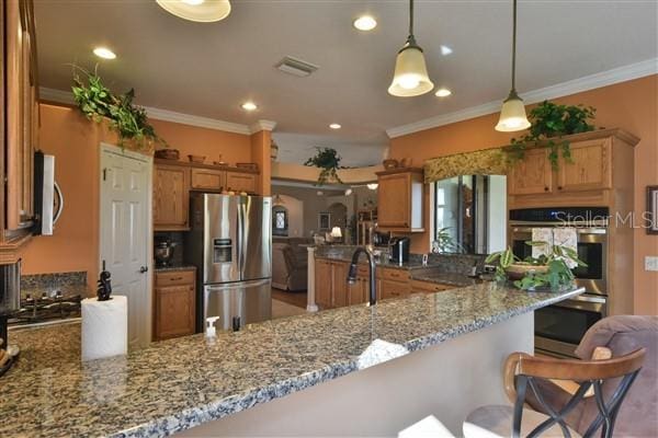 kitchen featuring a breakfast bar area, kitchen peninsula, pendant lighting, and stainless steel appliances