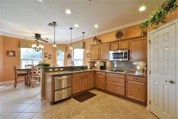 kitchen with kitchen peninsula, stainless steel appliances, ceiling fan, sink, and hanging light fixtures