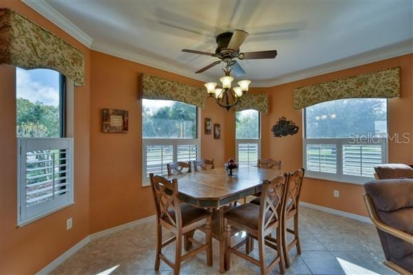 tiled dining room featuring ceiling fan with notable chandelier and crown molding