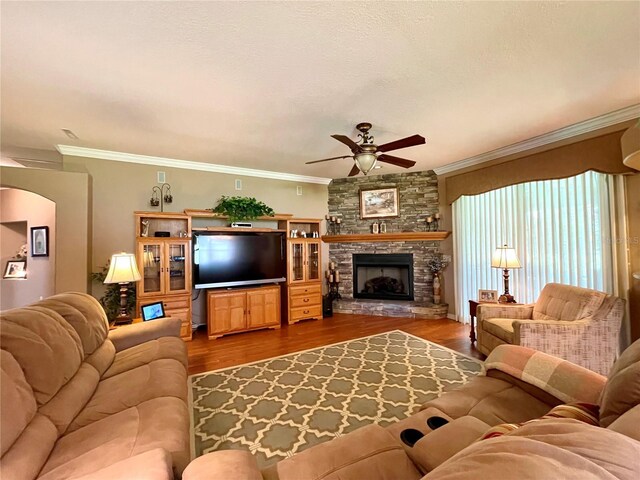 living room featuring hardwood / wood-style floors, ceiling fan, crown molding, and a fireplace