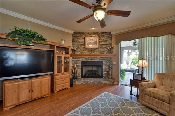 living room with light hardwood / wood-style floors, ornamental molding, and a fireplace