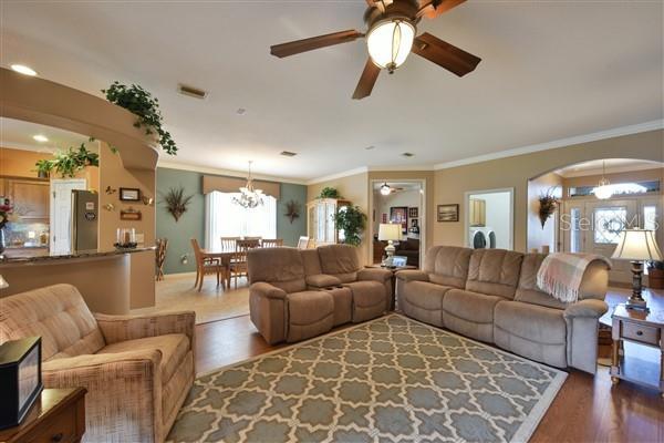 living room featuring french doors, dark wood-type flooring, ceiling fan with notable chandelier, and ornamental molding