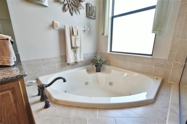 bathroom with vanity and tiled bath