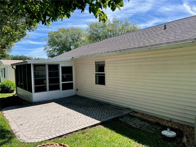 rear view of property featuring a sunroom and a patio area