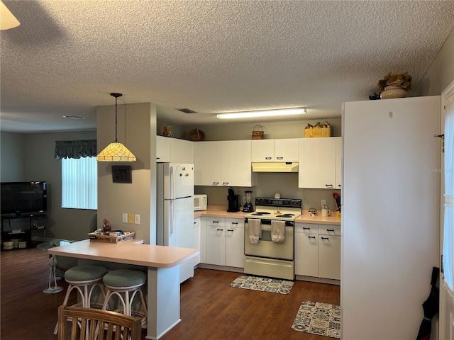 kitchen featuring white appliances, pendant lighting, dark wood-type flooring, a textured ceiling, and a kitchen bar