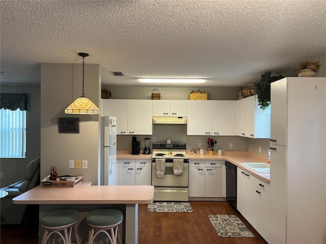 kitchen with dark hardwood / wood-style floors, white appliances, decorative light fixtures, a textured ceiling, and white cabinetry