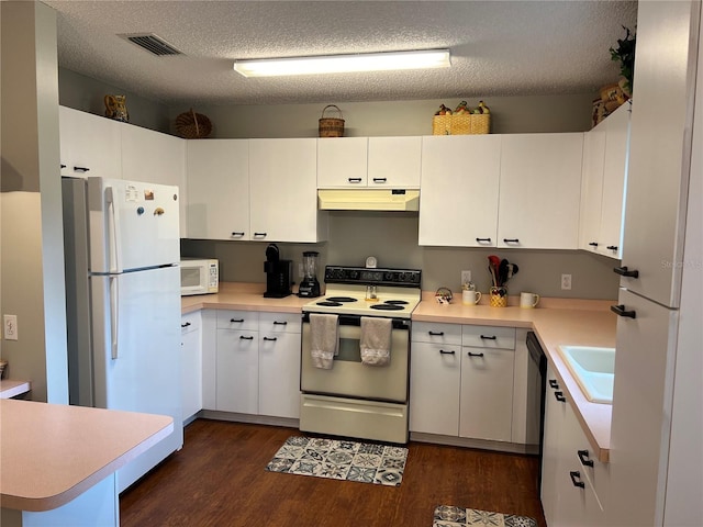 kitchen with white cabinets, dark hardwood / wood-style flooring, white appliances, and a textured ceiling