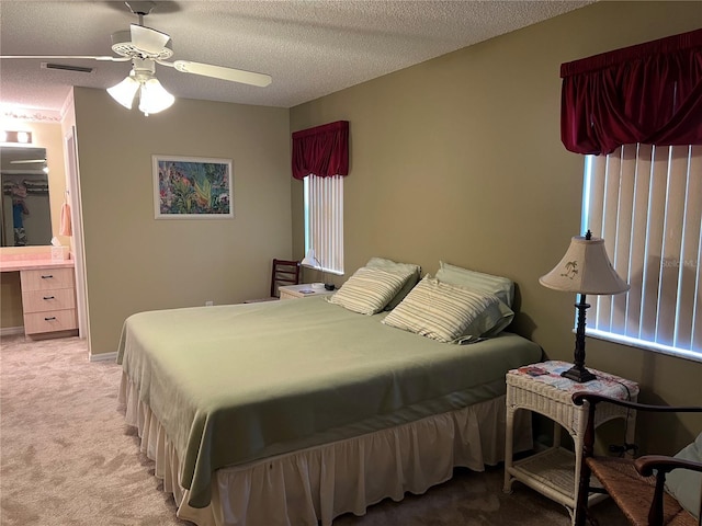 carpeted bedroom featuring ensuite bath, ceiling fan, and a textured ceiling