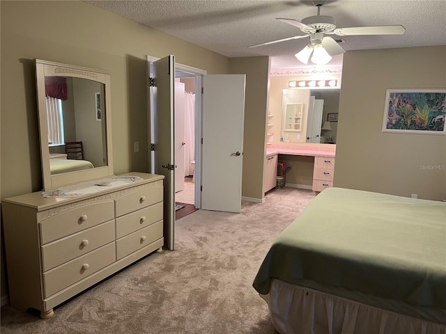 bedroom featuring light colored carpet, ensuite bath, ceiling fan, and a textured ceiling