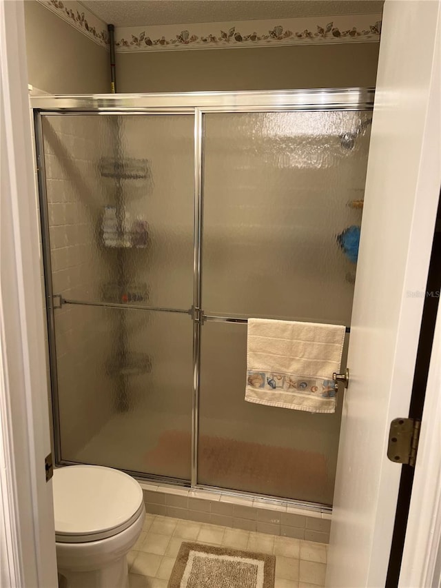 bathroom featuring a shower with shower door, tile flooring, and toilet