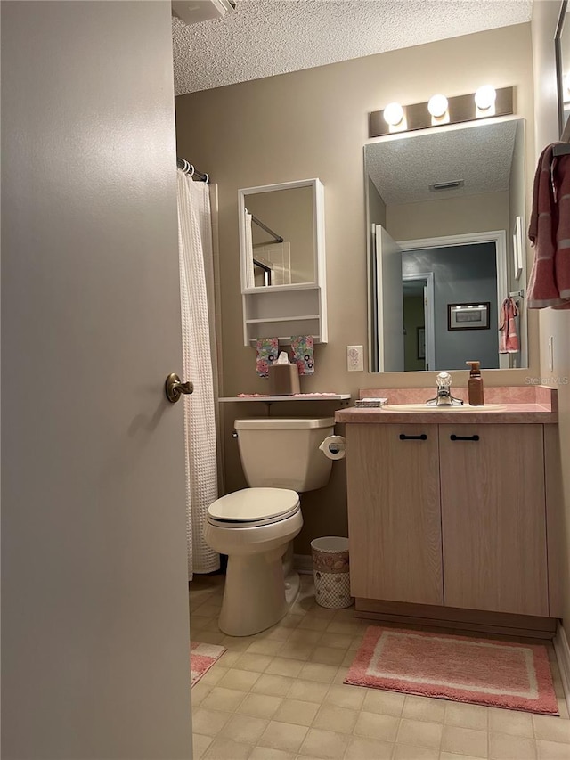 bathroom featuring tile floors, vanity with extensive cabinet space, a textured ceiling, and toilet