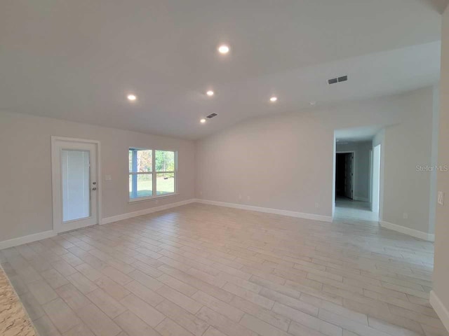 spare room with lofted ceiling and light wood-type flooring