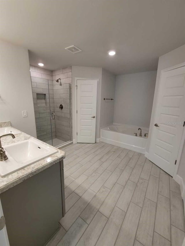 5243 SW 106th St, Ocala, FL 34476 - bathroom with a stall shower, a garden tub, double vanity, wood finished floors, and baseboards