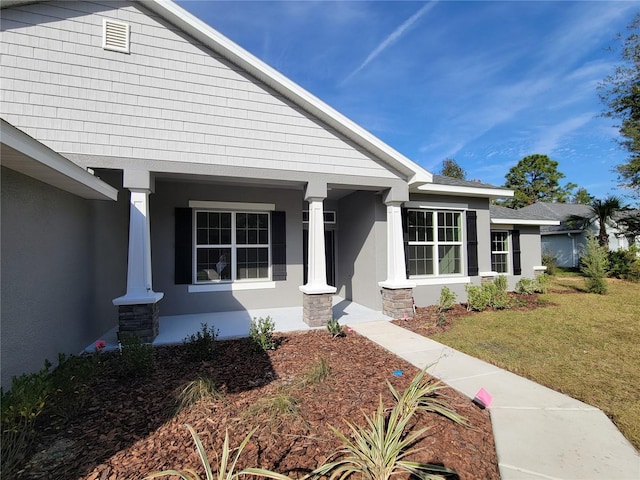 5243 SW 106th St, Ocala, FL 34476 - doorway to property featuring stucco siding, a lawn, and covered porch