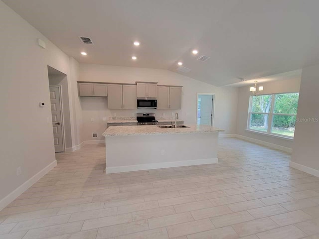 kitchen with sink, stainless steel appliances, light stone counters, an island with sink, and vaulted ceiling