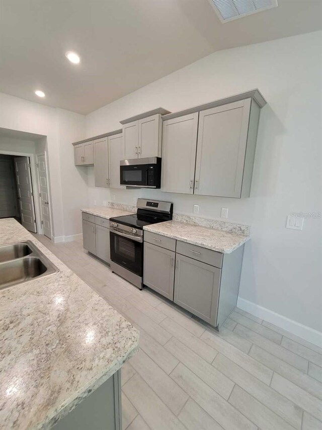 kitchen featuring appliances with stainless steel finishes, light wood-type flooring, gray cabinets, and sink