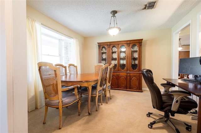 dining area featuring light colored carpet and a textured ceiling