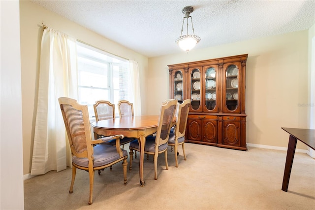 dining room featuring light colored carpet and a textured ceiling