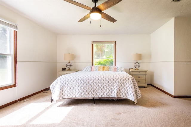 bedroom featuring light carpet, multiple windows, and ceiling fan