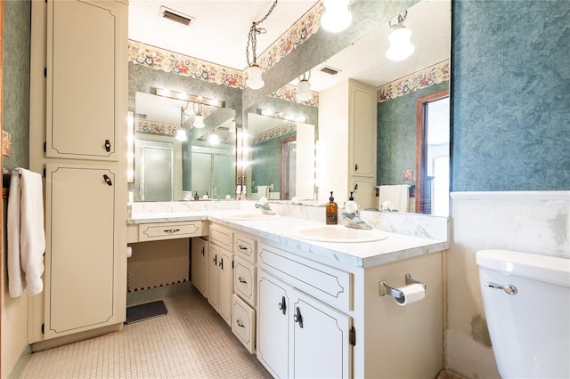 bathroom with tile patterned floors, vanity, toilet, and a textured ceiling