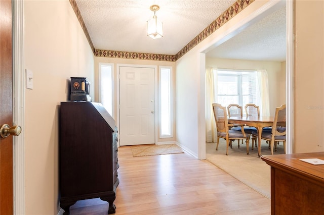 entrance foyer with a textured ceiling and light hardwood / wood-style flooring