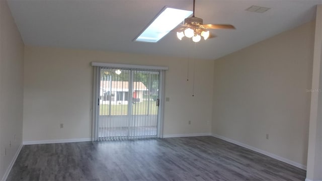 spare room with a skylight, ceiling fan, and dark hardwood / wood-style floors