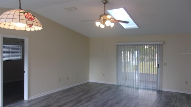 spare room featuring dark hardwood / wood-style flooring, ceiling fan, and vaulted ceiling with skylight