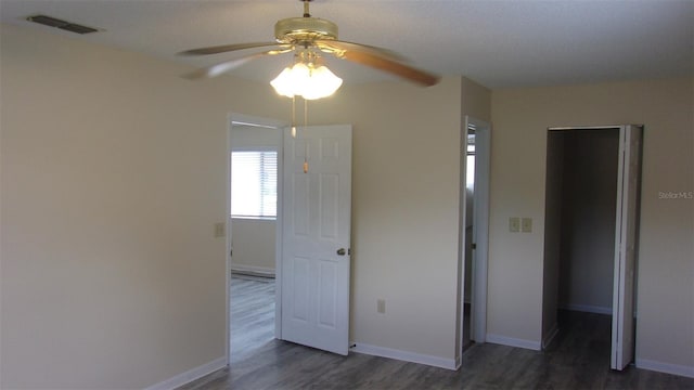 unfurnished bedroom with ceiling fan, dark wood-type flooring, and a closet