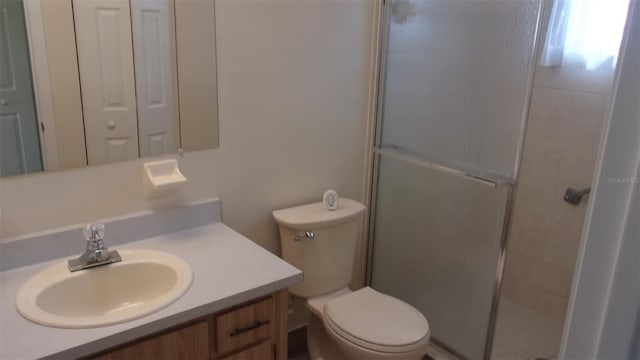 bathroom with vanity, toilet, and a shower with door