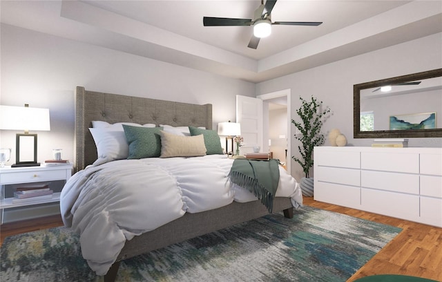 bedroom with ceiling fan, a tray ceiling, and light wood-type flooring