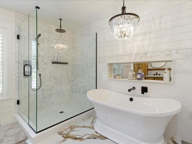 bathroom with shower with separate bathtub and an inviting chandelier