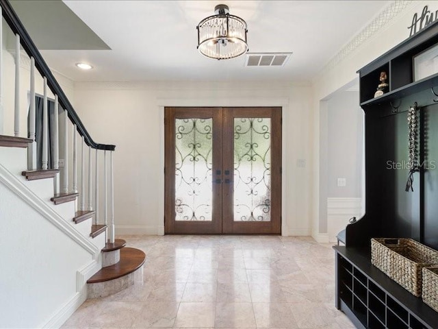 foyer featuring french doors, crown molding, and a notable chandelier