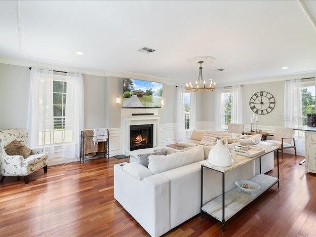 living room featuring crown molding, dark hardwood / wood-style flooring, and an inviting chandelier