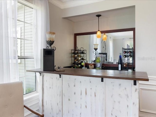 bar with pendant lighting and ornamental molding