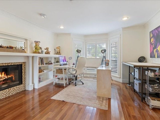 home office with a tiled fireplace, crown molding, and hardwood / wood-style floors