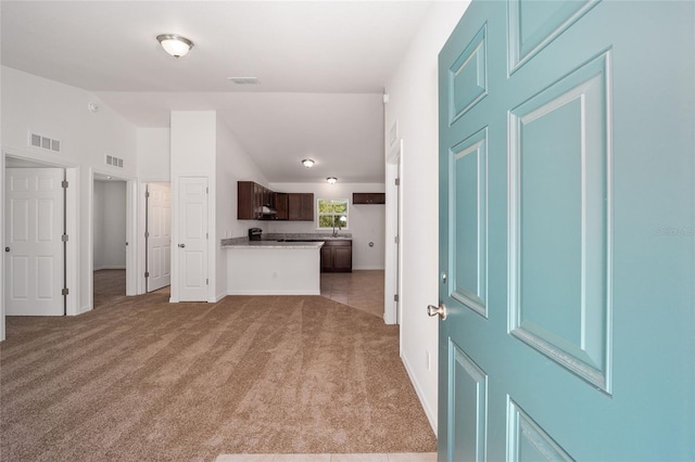 unfurnished living room featuring light carpet, lofted ceiling, and sink