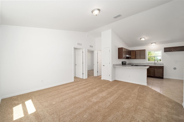 kitchen featuring kitchen peninsula, light carpet, stainless steel range with electric stovetop, dark brown cabinets, and vaulted ceiling