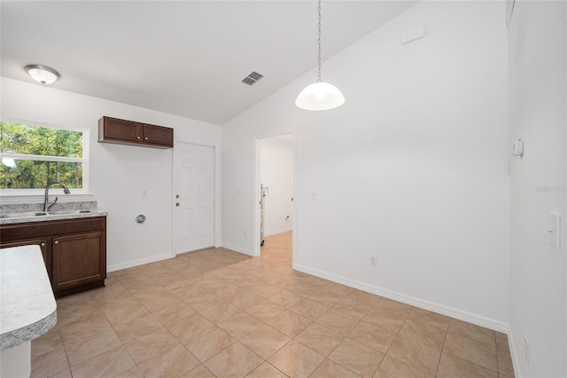 kitchen with dark brown cabinetry, sink, hanging light fixtures, lofted ceiling, and light tile patterned flooring