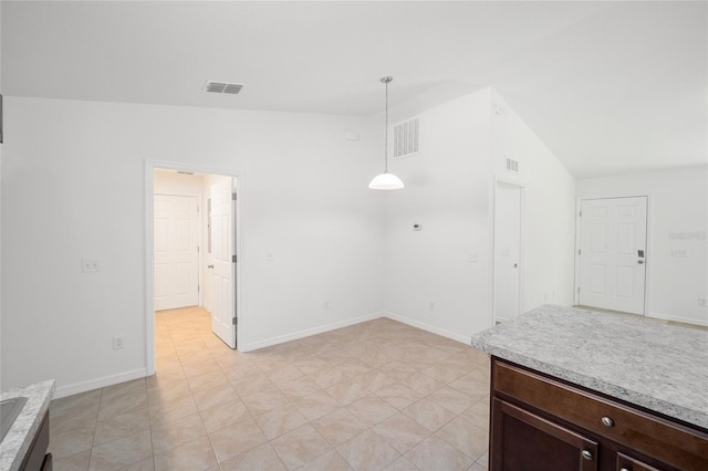 interior space with pendant lighting, vaulted ceiling, light tile patterned floors, and dark brown cabinets